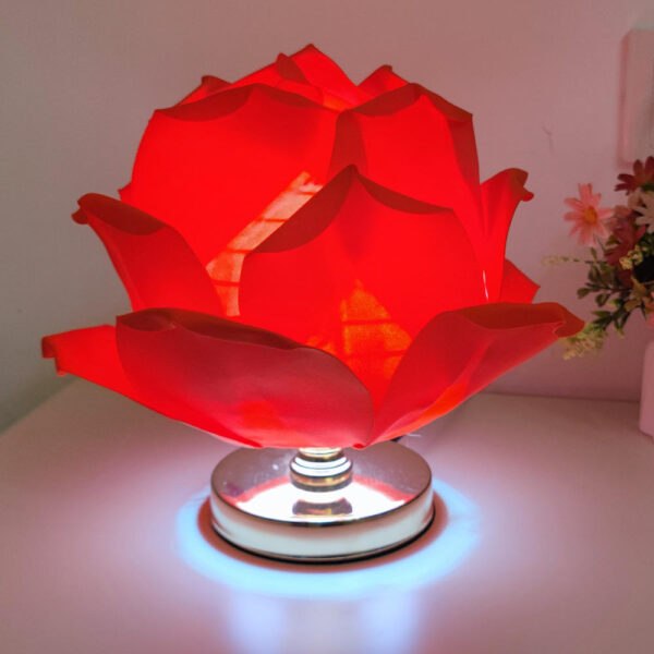Red flower-shaped table lamp with soft glowing light on gold base