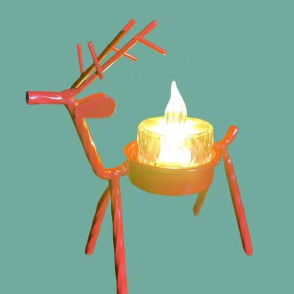 Orange metal deer tealight candle holder with a glowing candle, festive Christmas table decoration.