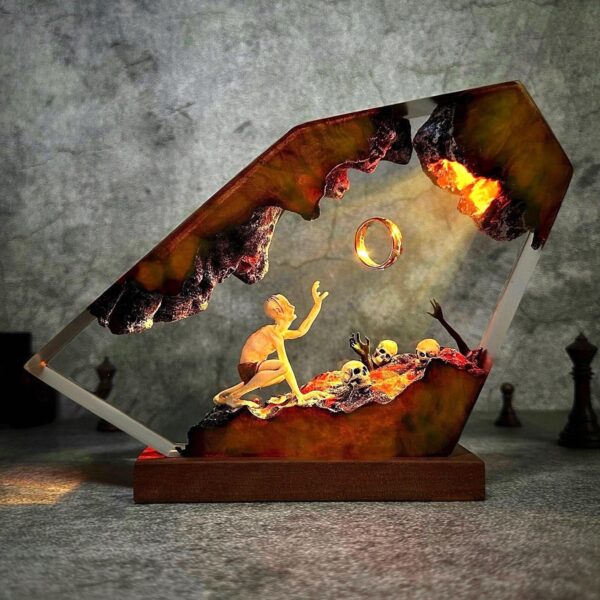 Resin art lamp featuring a cave scene with a creature reaching toward a glowing golden ring, illuminated with warm orange LED lighting.