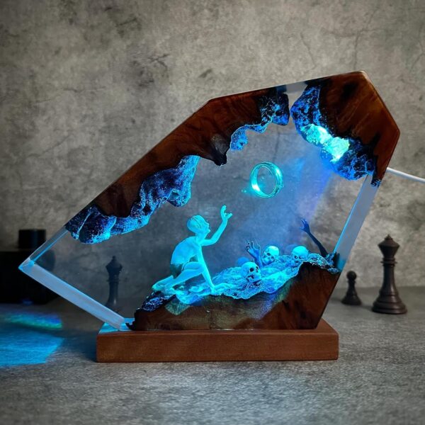 Handcrafted resin and wood art lamp featuring a glowing cave scene with a creature reaching toward a floating ring and illuminated skull details.