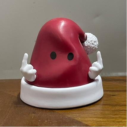 Red Liver-Shaped Anthropomorphic Decorative Ornament (With White Hands) on White Base, Placed on Wooden Surface