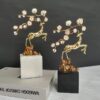 Light Luxury Brass Plum Blossom Deer Sculptures A pair of light luxury decorative ornaments featuring polished brass deer sculptures in leaping poses, paired with enamel plum blossom branches, mounted on white and black marble bases respectively. Displayed against a dark backdrop with art books, the design blends traditional Chinese auspicious symbolism with modern craftsmanship, ideal for modern luxury, new Chinese, or minimalist interiors