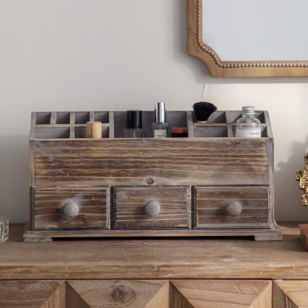 A rustic wooden makeup organizer filled with cosmetics, sitting on a wooden vanity table in a farmhouse style bedroom. A vintage mirror hangs on the wall in the background.
