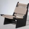 A wabi-sabi style lounge chair featuring a sleek black solid wood frame and handwoven natural rope upholstery on the backrest and seat. Displayed against a clean white background, it highlights the contrast between the sturdy frame and breathable woven texture, ideal for modern, serene home spaces.