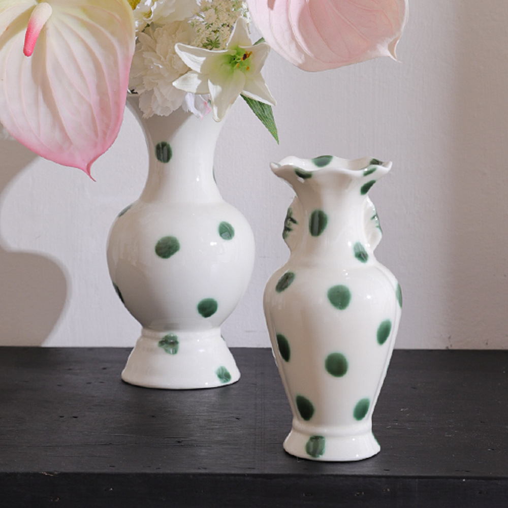 Green dot ceramic vase pair with floral arrangement