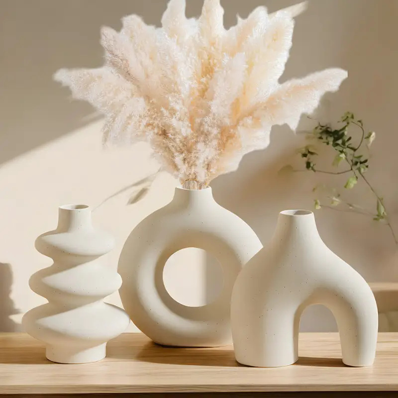 Matte white ceramic vase trio with dried pampas grass in warm natural light