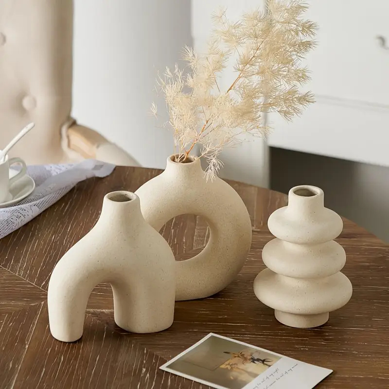 Boho geometric ceramic vases in matte cream finish decorating a round wooden coffee table