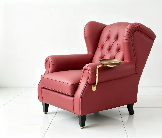 Wine-red vintage club armchair with brass swivel tray for coffee cup, three-quarter view