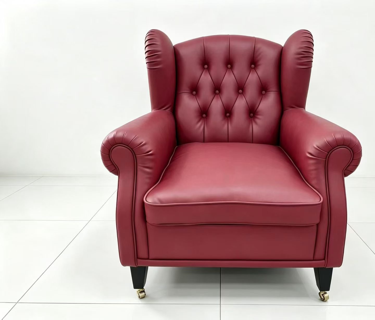 Vintage burgundy wingback club armchair with deep button tufting, rolled arms and brass casters, front view